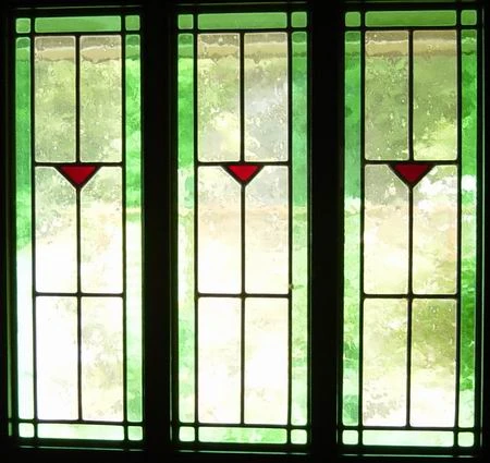 Three green-bordered stained-glass window panels